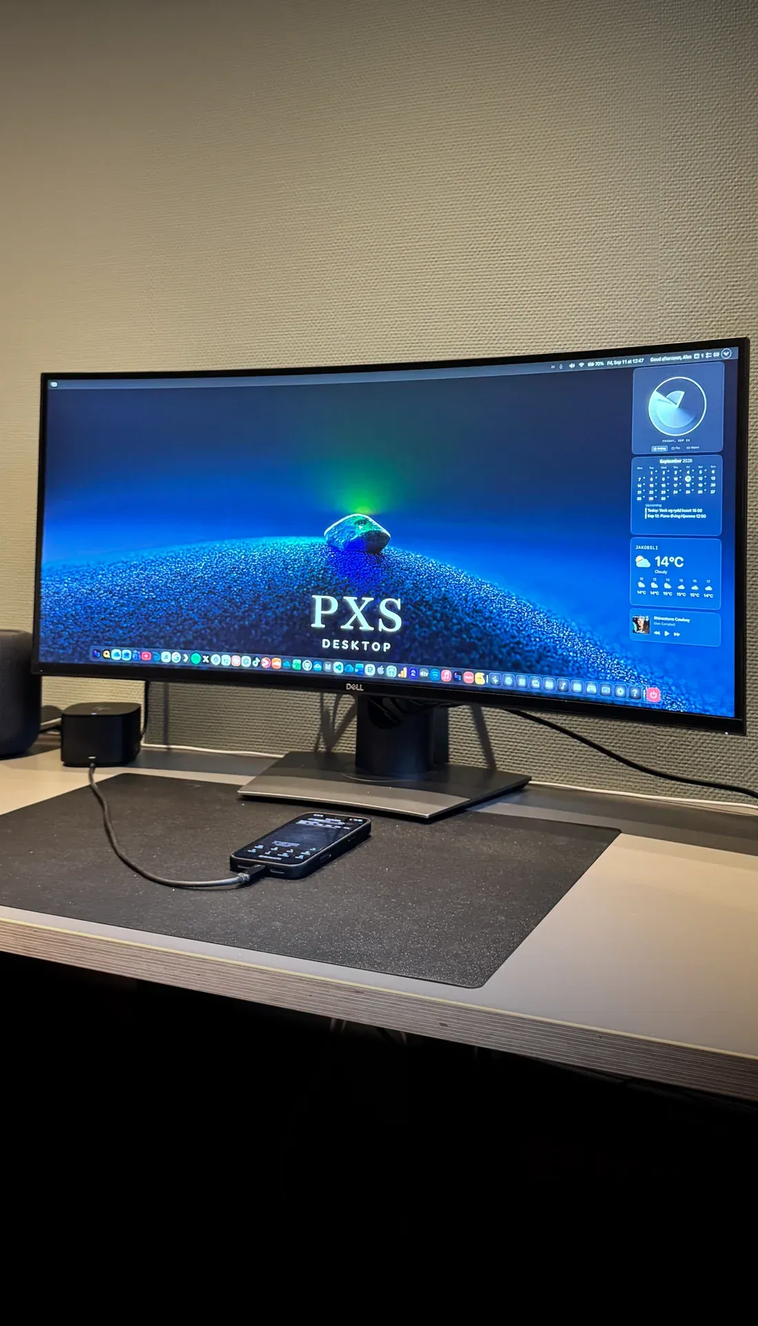 An iPhone cabled to a desk monitor running PXS.